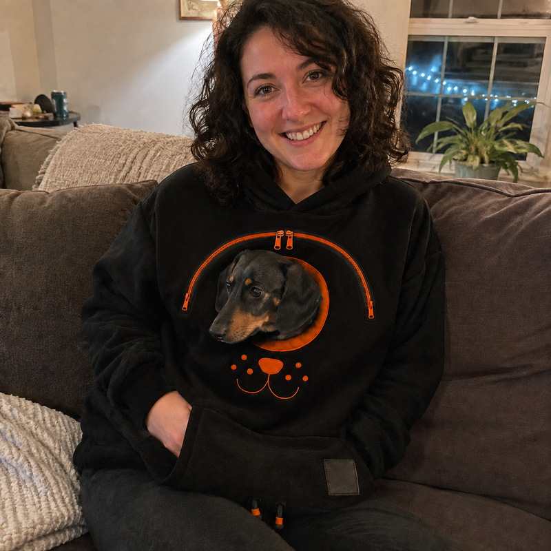 Pet parent relaxing on a couch with a dachshund in the hoodie pouch